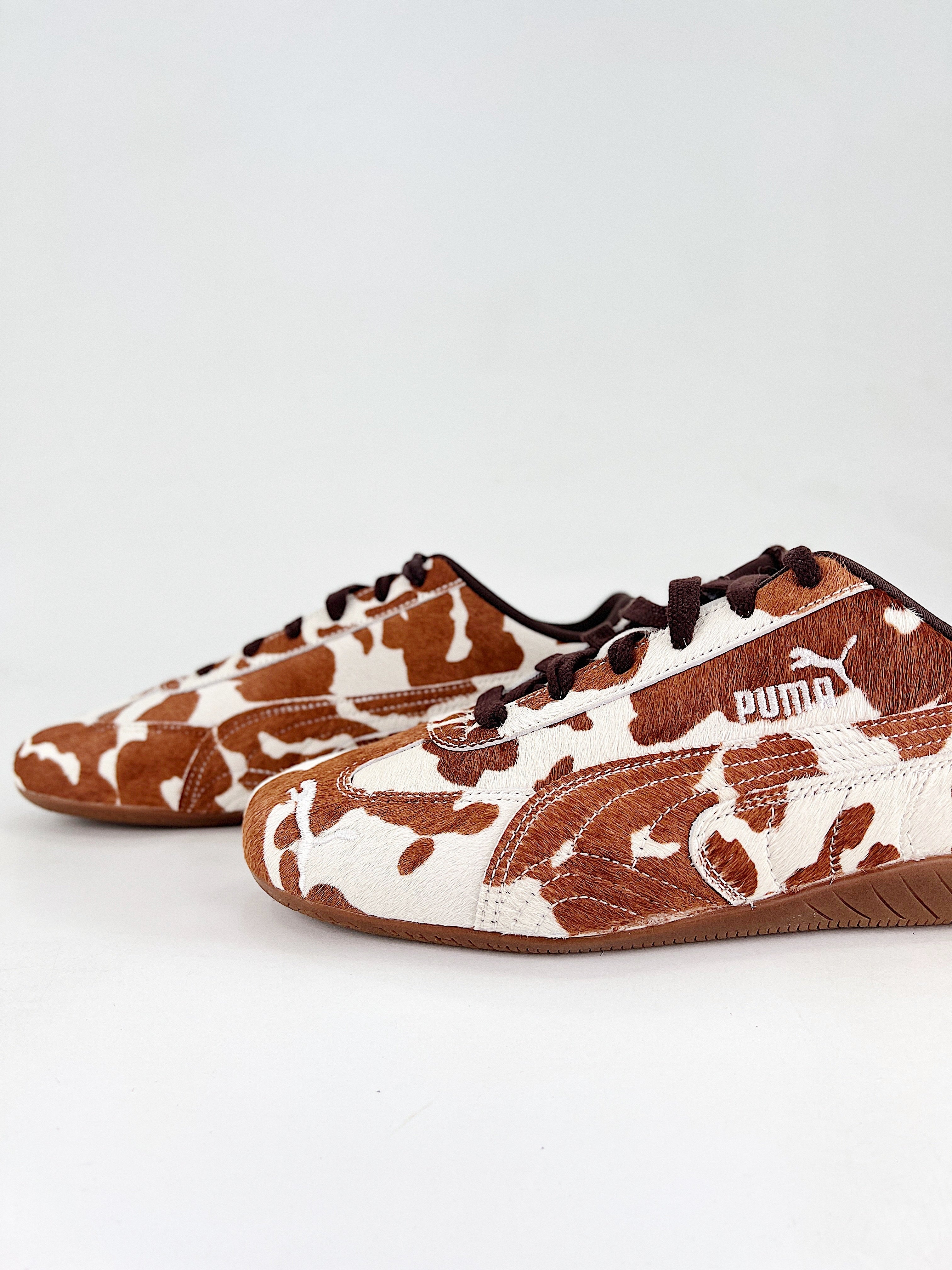 Pair of brown and white patterned sneakers on a light gray background